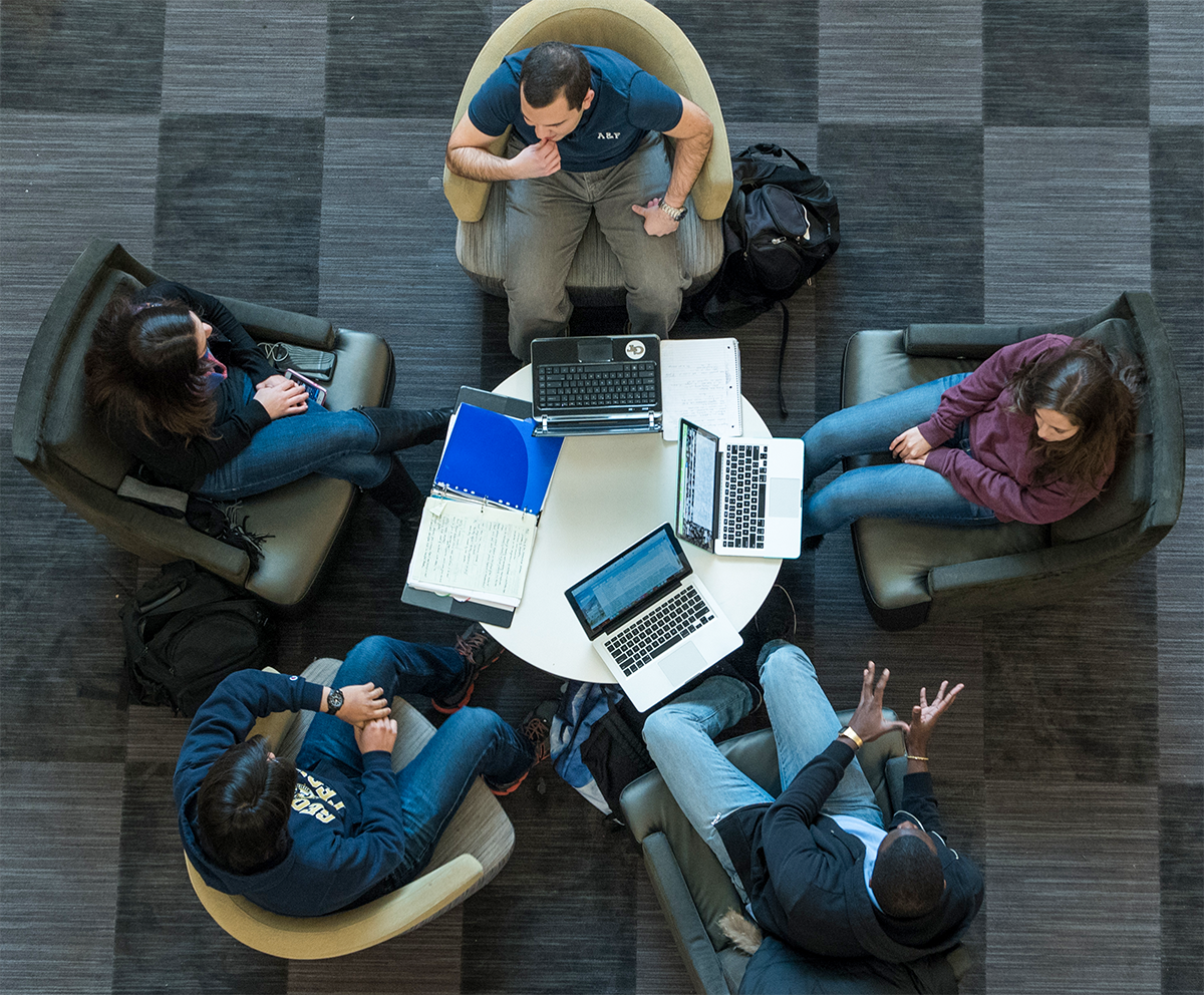 Look from above of people meeting sitting in a circle with a table in the middle.